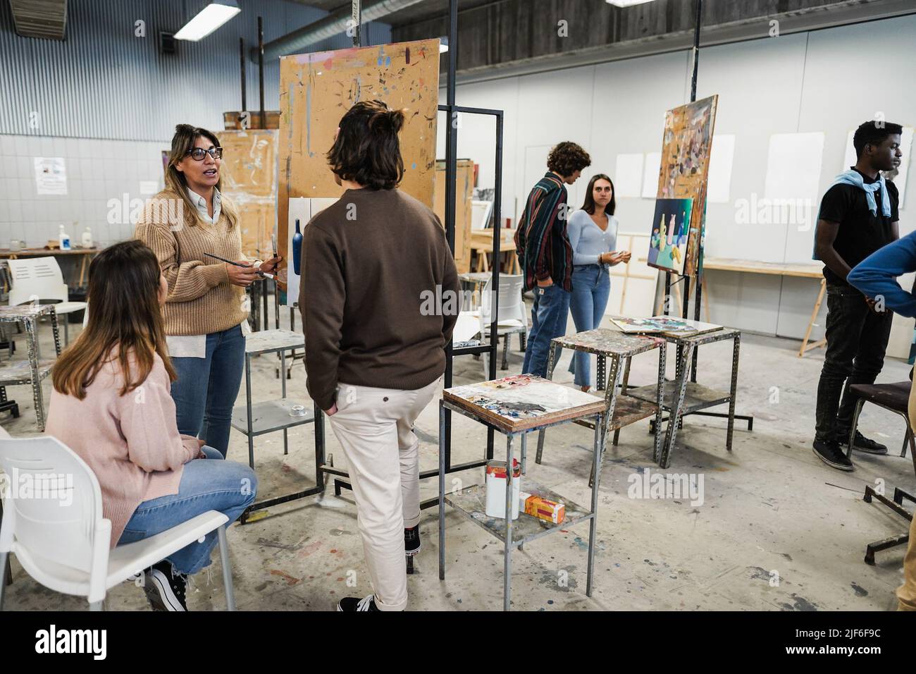 Reifer Lehrer, der während des Malens in der Schule mit Kunststudenten arbeitet - Fokus auf das Gesicht der Frau Stockfoto