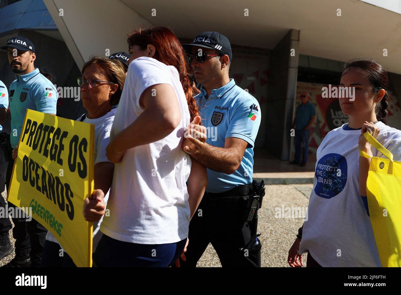 Greenpeace-Aktivisten werden von der Polizei gedrängt, während sie Transparente halten, auf denen stand: „Protect the Oceans“ während einer Demonstration vor der UN-Ozeankonferenz in Lissabon, Portugal, am 30. Juni 2022. REUTERS/Pedro Nunes Stockfoto