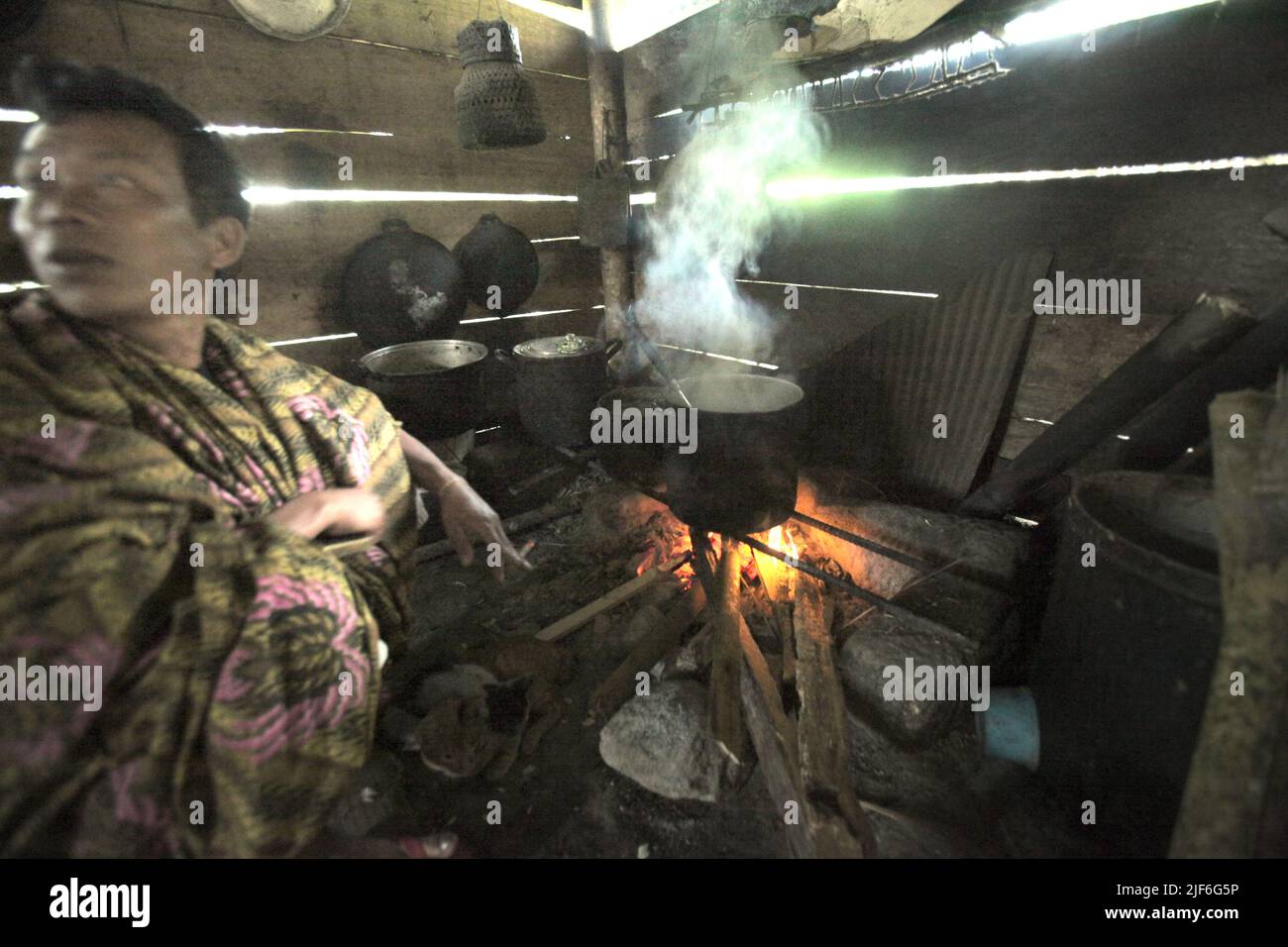 Ein Mann, der mit Feuerholz in einer Hausküche in Piongan Village, North Toraja, South Sulawesi, Indonesien, kocht. Stockfoto
