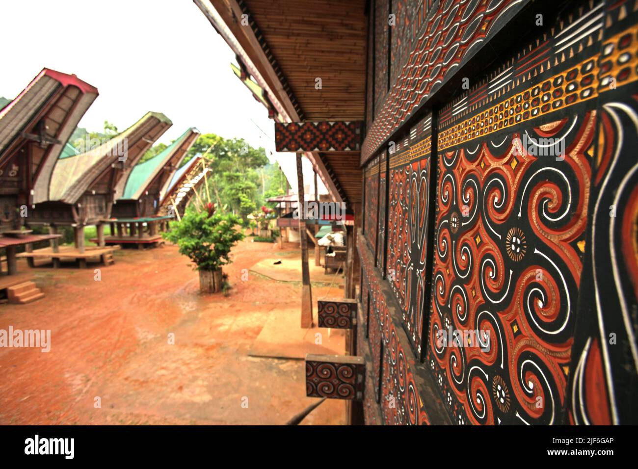 Wandschnitzereien an der Hauswand und Reisestangen in traditioneller Toraja-Architektur im Dorf Ma'dong, Nord-Toraja, Süd-Sulawesi, Indonesien. Stockfoto