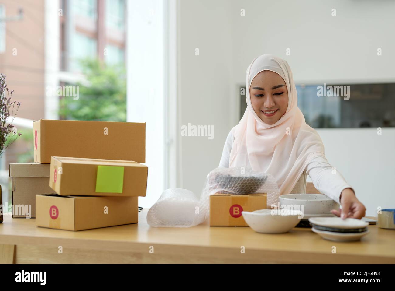 KMU freiberufliche Frau muslim arbeitet mit Verpackung Startup Unternehmer Kleinunternehmer zu Hause, Online-Geschäft Verkäufer Verpackung und Lieferung Stockfoto
