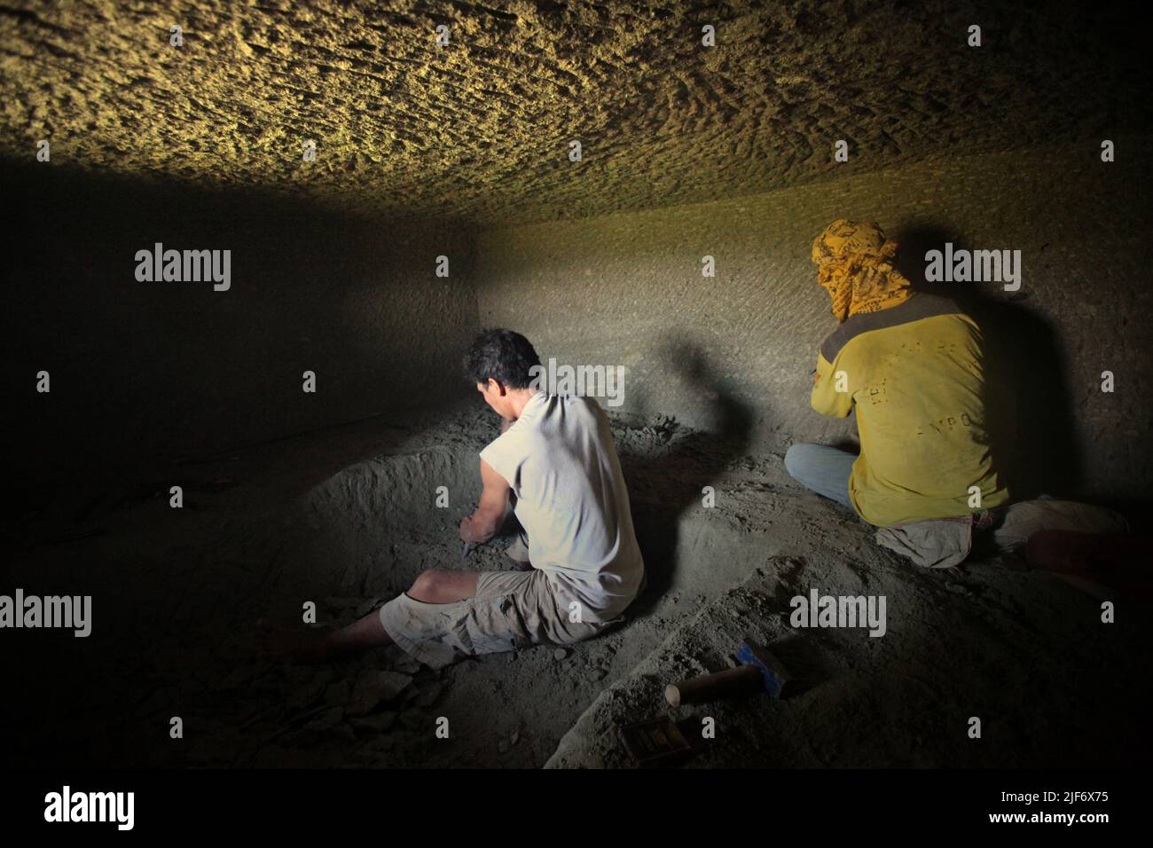 Arbeiter graben und schnitzen durch Felsen, um eine Kammer für das traditionelle Steinkammergrab in Nord-Toraja, Süd-Sulawesi, Indonesien zu bauen. Stockfoto