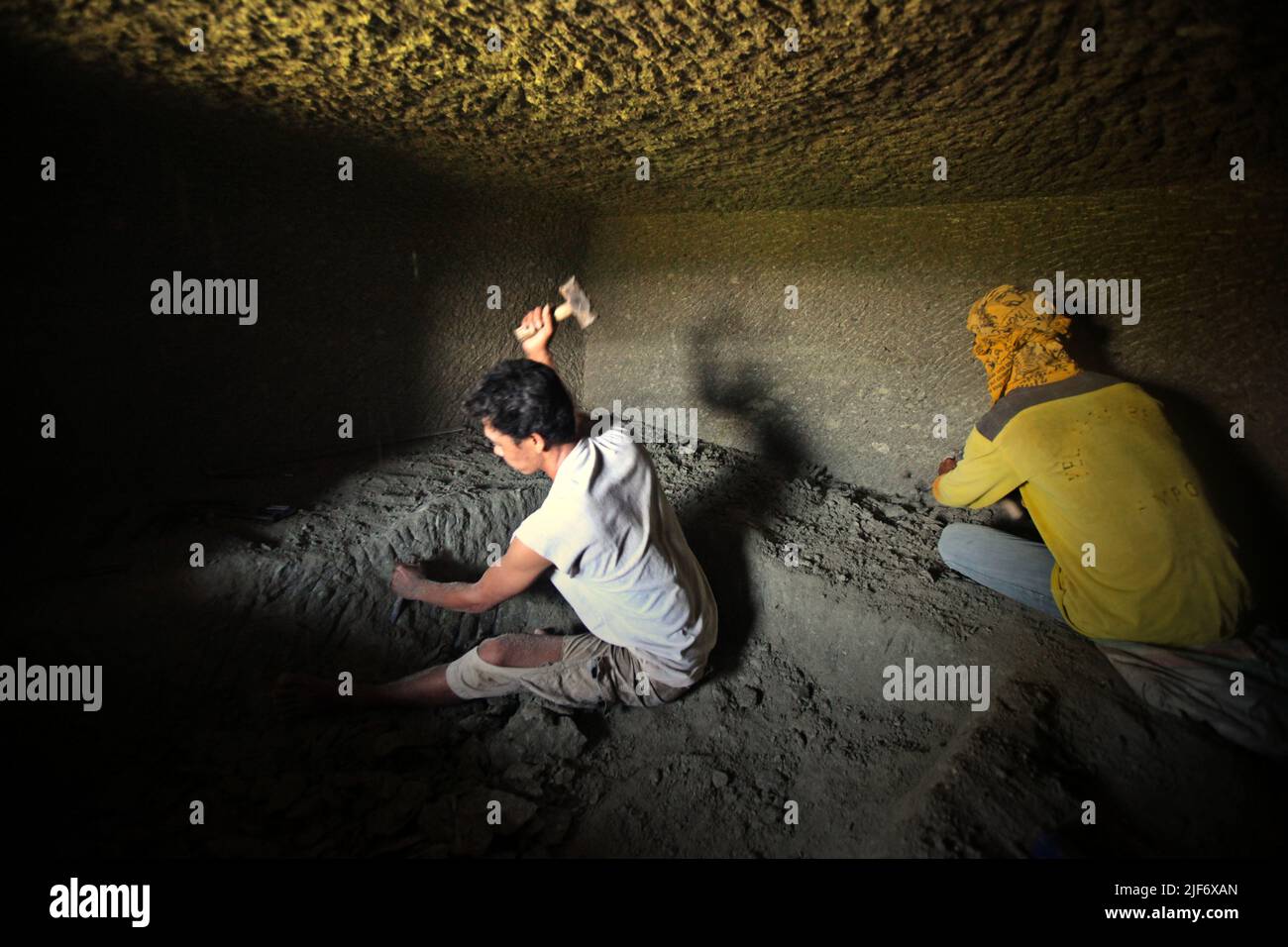 Arbeiter graben und schnitzen durch Felsen, um eine Kammer für das traditionelle Steinkammergrab in Nord-Toraja, Süd-Sulawesi, Indonesien zu bauen. Stockfoto