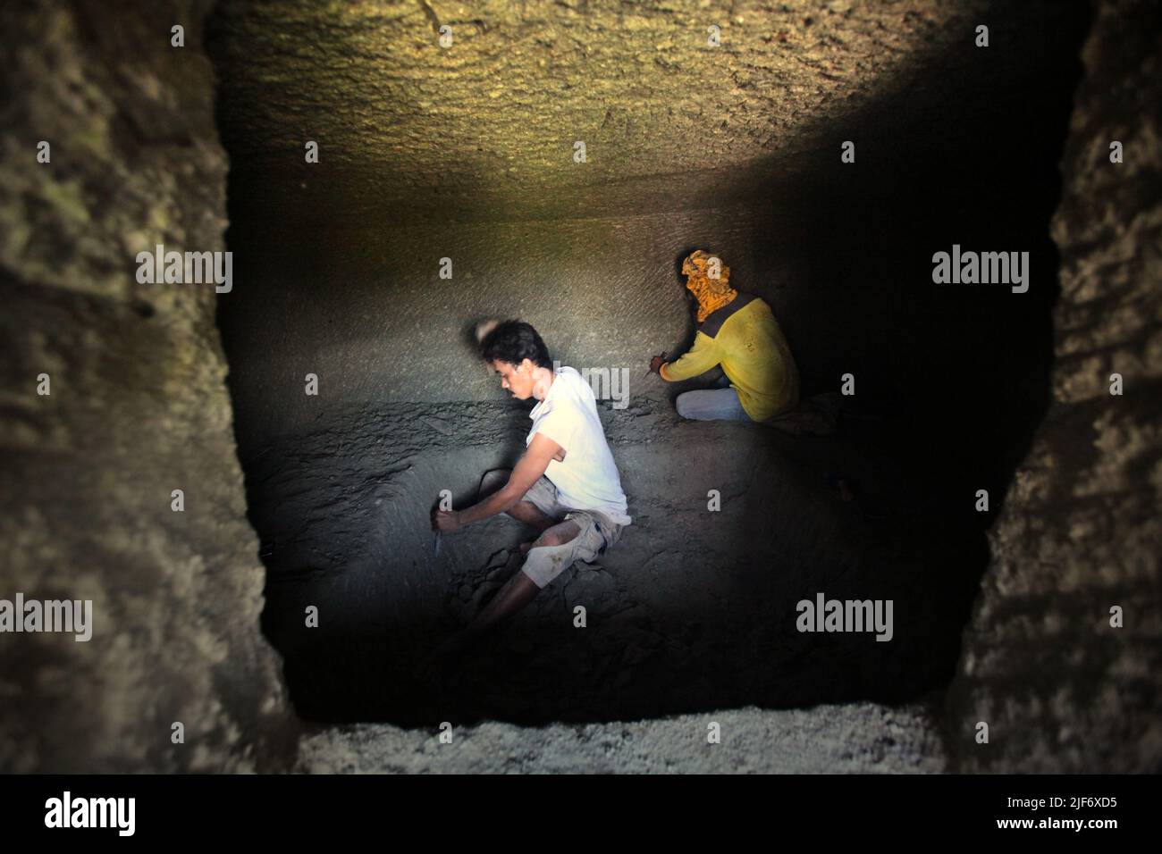 Arbeiter graben und schnitzen durch Felsen, um eine Kammer für das traditionelle Steinkammergrab in Nord-Toraja, Süd-Sulawesi, Indonesien zu bauen. Stockfoto