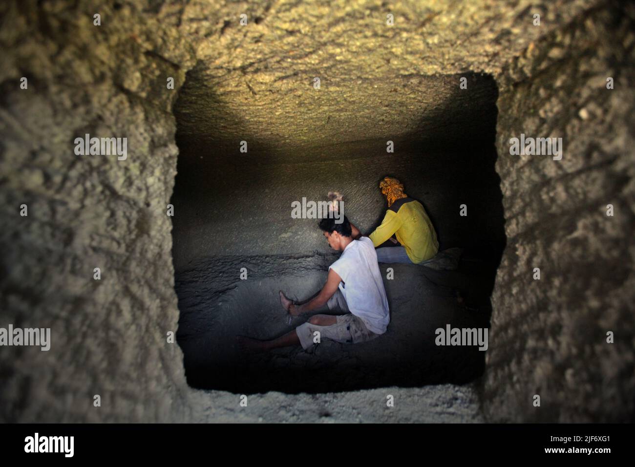 Arbeiter graben und schnitzen durch Felsen, um eine Kammer für das traditionelle Steinkammergrab in Nord-Toraja, Süd-Sulawesi, Indonesien zu bauen. Stockfoto