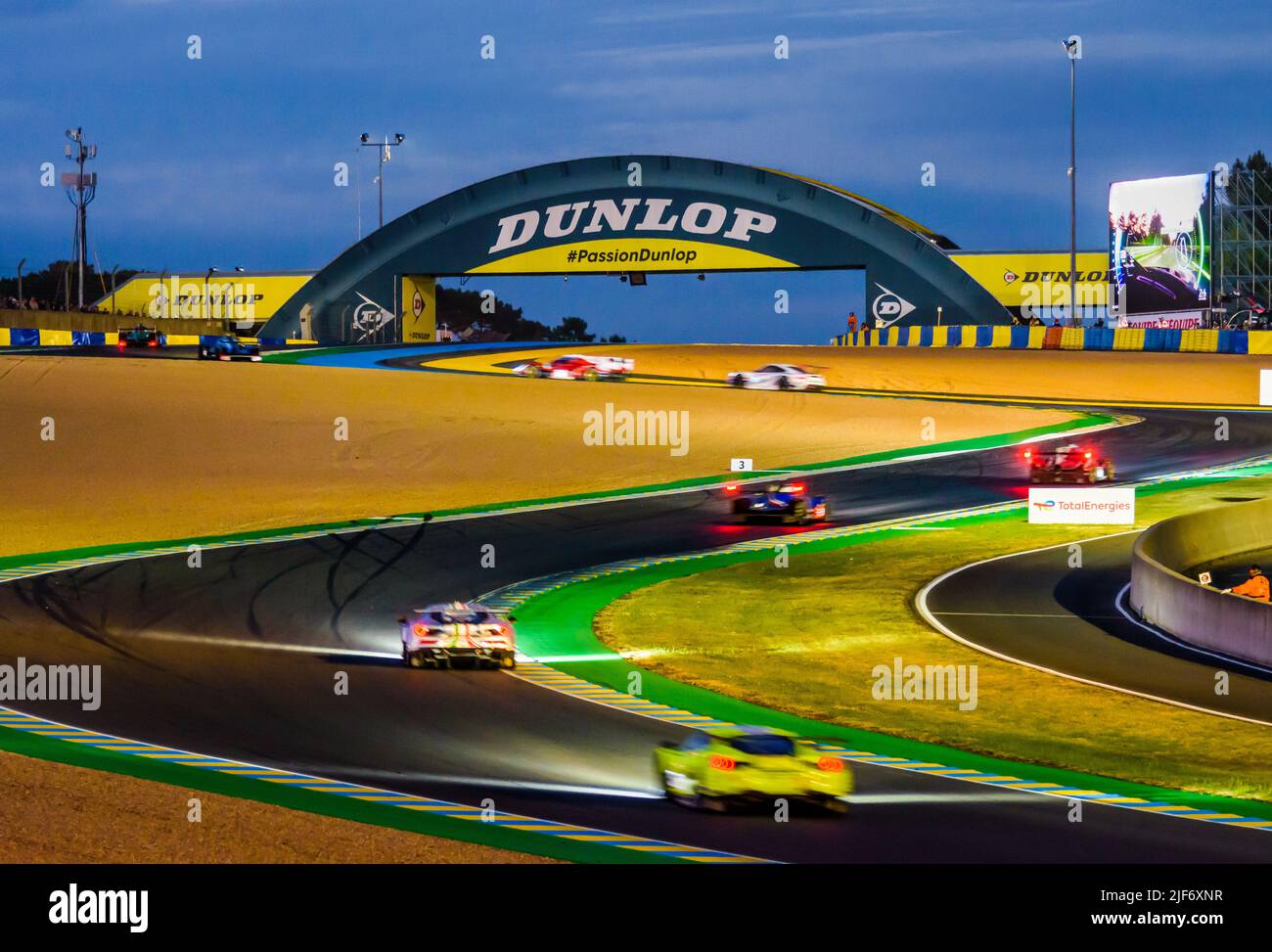 Rennwagen fahren nachts über die Dunlop-Schikane, bevor sie während der 24 Stunden von Le Mans unter der Dunlop-Fußgängerbrücke auf dem Circuit de la Sarthe fahren. Stockfoto