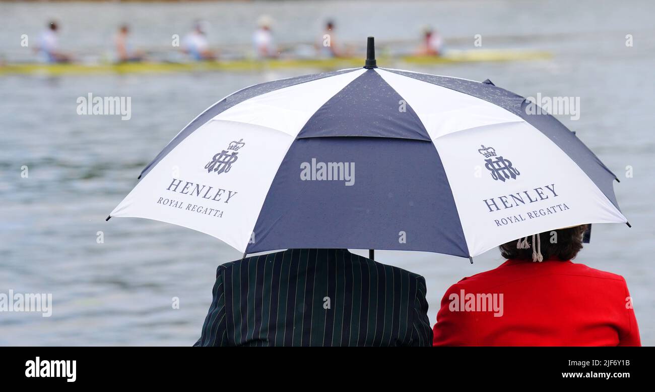 Besucher der Stewards' Enclosure beobachten das Rennen, während sie sich während der Henley Royal Regatta 2022 an der Themse in Henley-on-Thames, Oxfordshire, unter einem Regenschirm abschirmen. Bilddatum: Donnerstag, 30. Juni 2022. Stockfoto