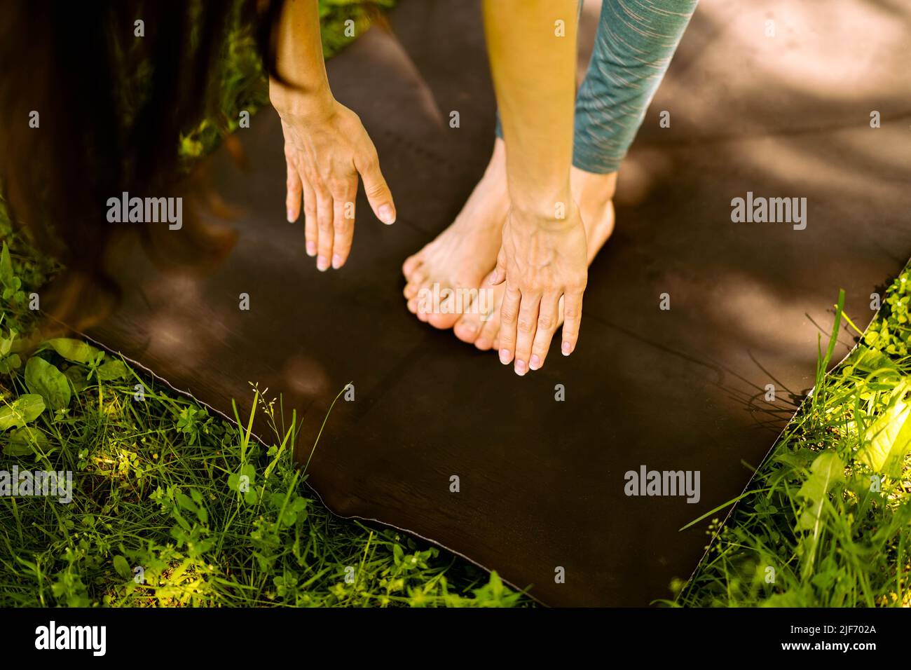 Ein junges, schönes Mädchen macht eine Übung im Park. Nahaufnahme. Das Konzept von Yoga, Fitness, gesunder Lebensstil, schlanker Körper und Ökologie. Seitenansicht Stockfoto