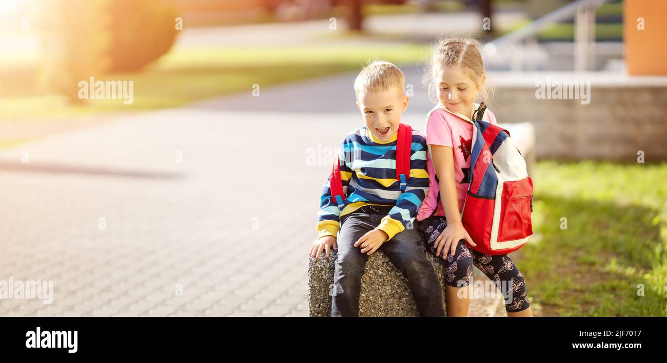 Junge und Mädchen sitzen auf dem Stein in der Nähe der Schule Stockfoto