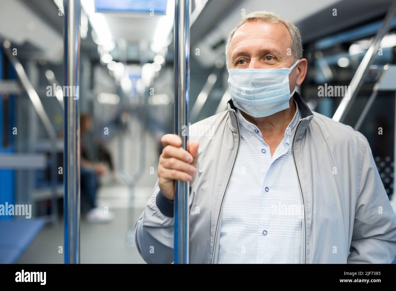 Mann mittleren Alters mit Gesichtsmaske im U-Bahn-Auto Stockfoto