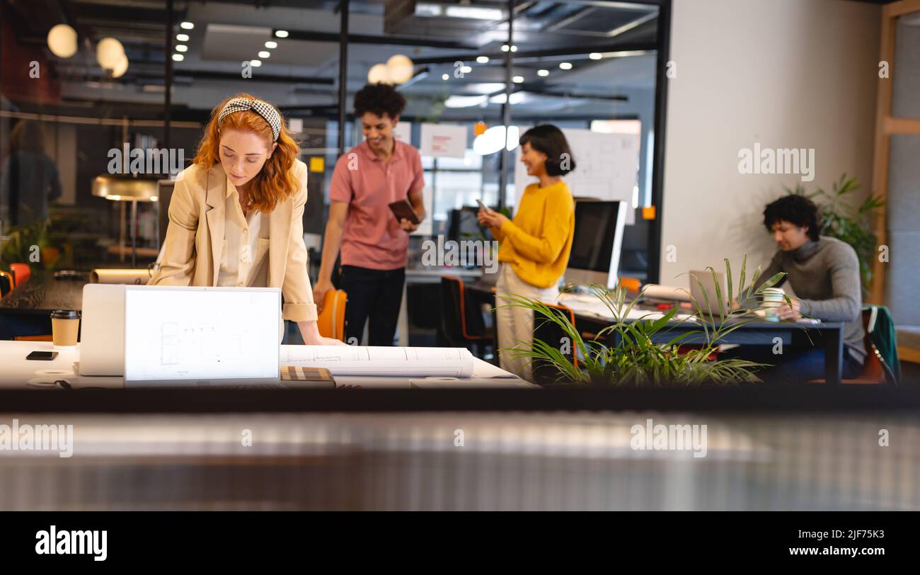 Kaukasische junge Geschäftsfrau, die am Schreibtisch im Büro am Laptop arbeitet Stockfoto