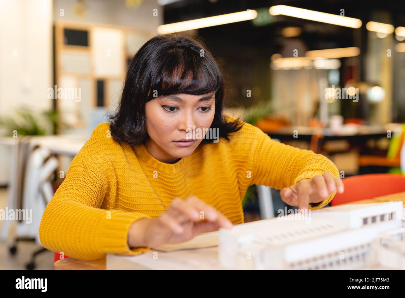 Biracial yfemale Architektin untersucht Architekturmodell in kreativen Büro Stockfoto