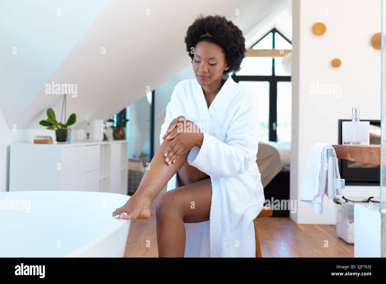 Afro junge afroamerikanische Frau streichelt ihr Bein im Badezimmer zu Hause, kopieren Raum Stockfoto