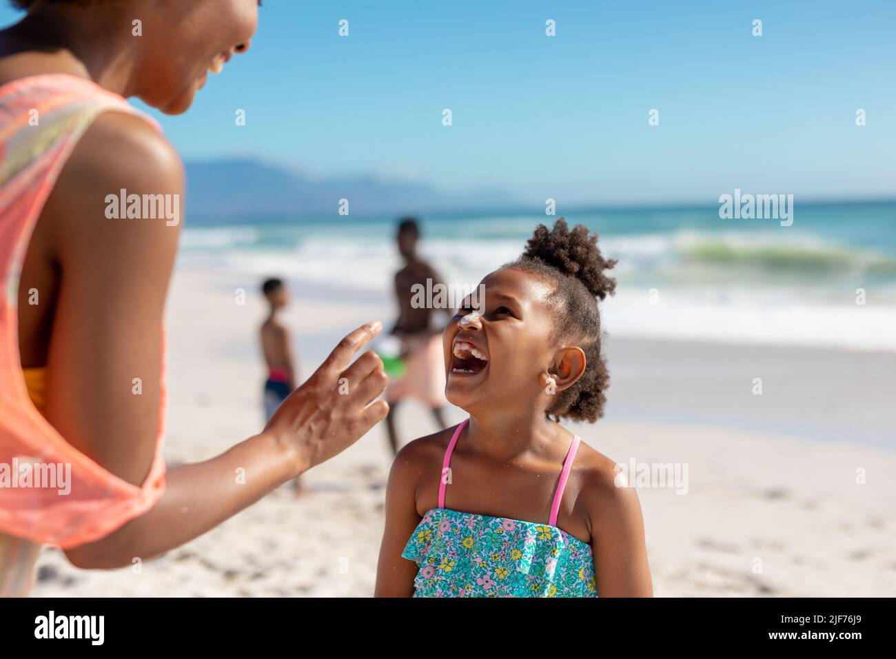 Fröhliche afroamerikanische Mutter und Tochter genießen sonnigen Tag am Strand mit Familie, Kopierer Platz Stockfoto