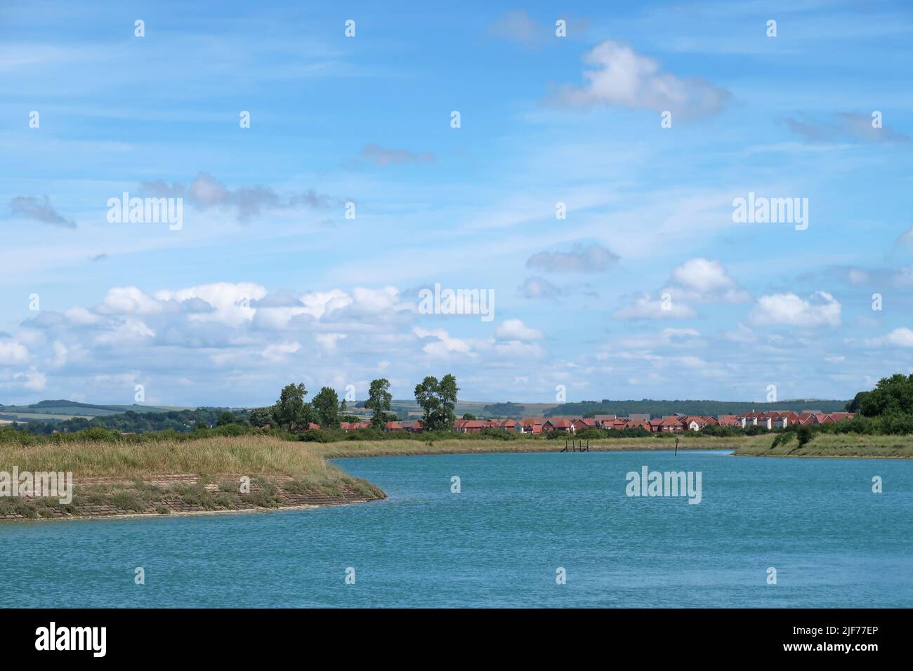 Das Ufer des Flusses Arun, in der Nähe von Littlehampton West Sussex. Zeigt Fluss bei Flut und neue Wohnsiedlung in Littlehampton in der Ferne Stockfoto