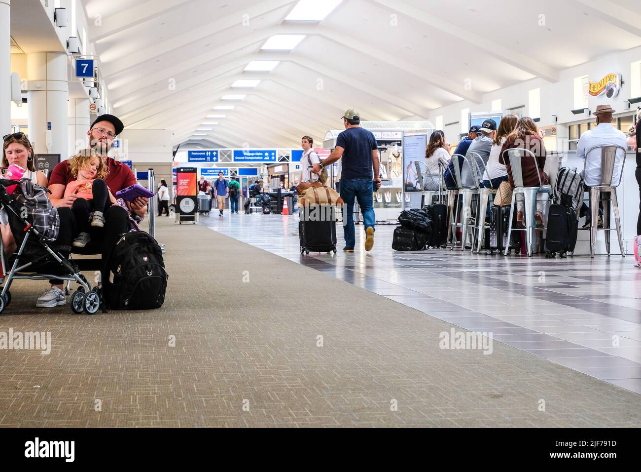 Flugausfälle belasten müde Reisende. Bilder von aktuellen Flugverspätungen in den USA. Passagiere, die am Gate warten. Flughafenconcourse. Stockfoto