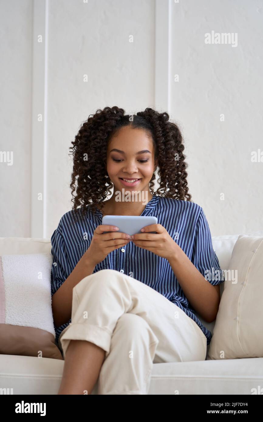 Glückliche Teenager afroamerikanische Mädchen spielen Handy-Spiel auf dem Telefon zu Hause. Stockfoto