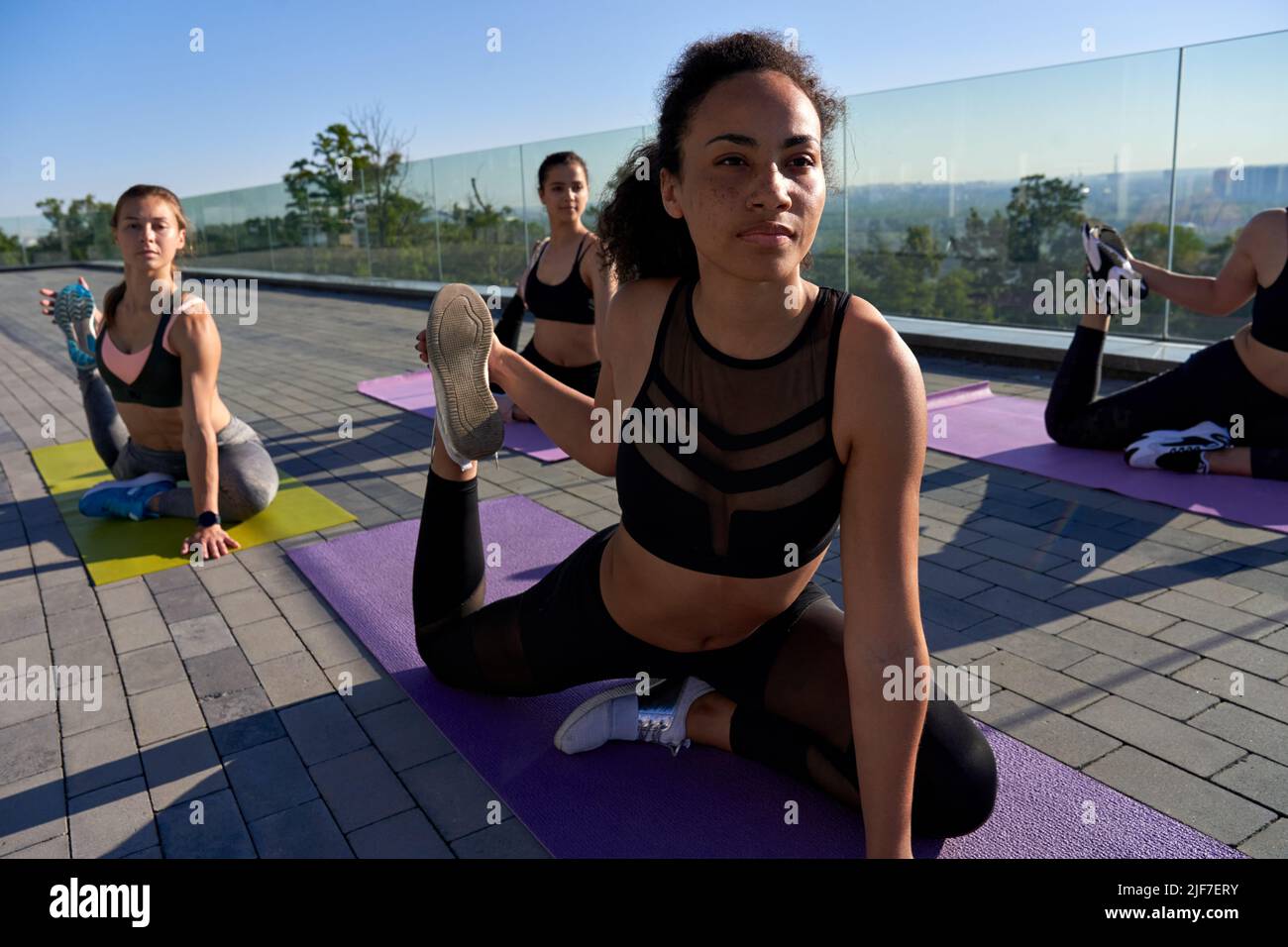 Fit Frau macht Yoga bei Outdoor-Gruppenkurs. Stockfoto
