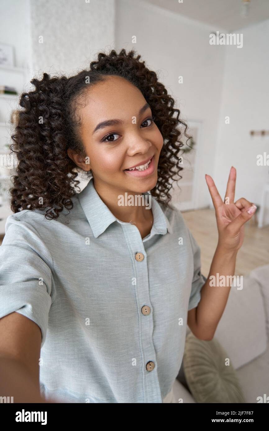 Junge glücklich afroamerikanischen Teenager-Mädchen halten Telefon Blick auf mobile Kamera. Stockfoto