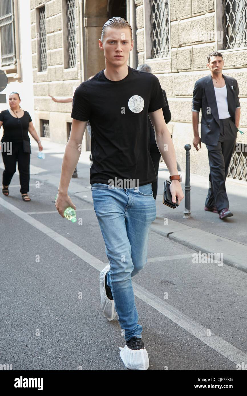 MAILAND, ITALIEN - 20. JUNI 2022: Mann mit schwarzem T-Shirt und blauer Denim-Hose vor der Giorgio Armani Fashion Show, Mailand Fashion Week Street Style Stockfoto