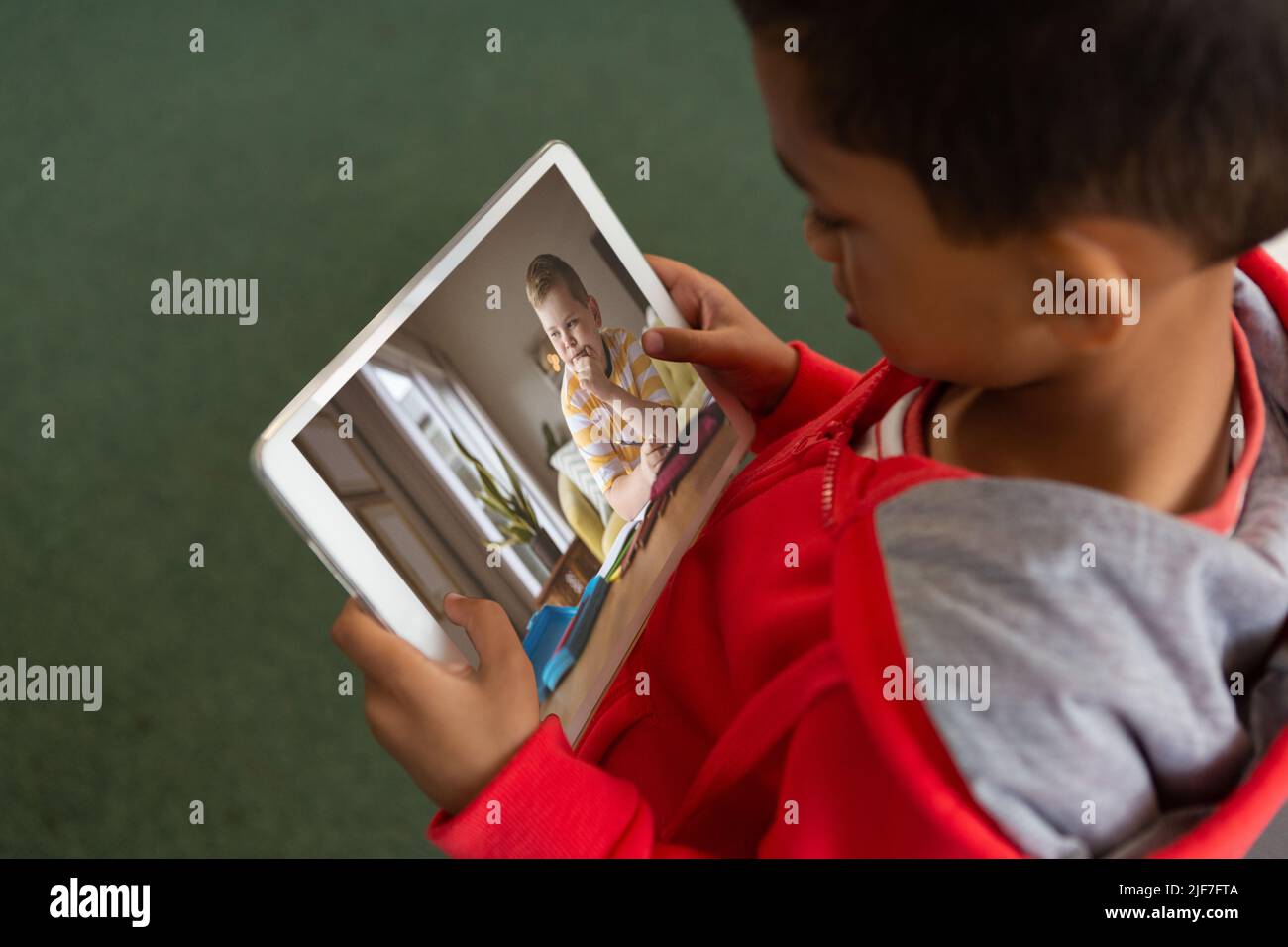 High-Angle-Ansicht des biracial Jungen Blick auf Freund durch Videoanruf auf dem digitalen Tablet-Bildschirm Stockfoto