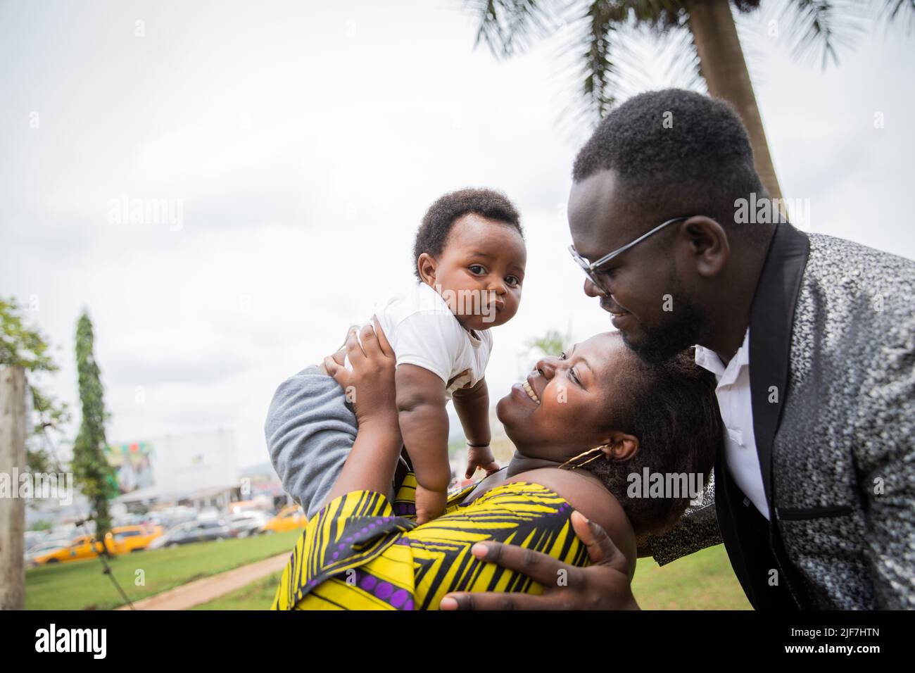 Afrikanische Familie glücklich zusammen, Mutter hebt Baby in der Luft. Stockfoto