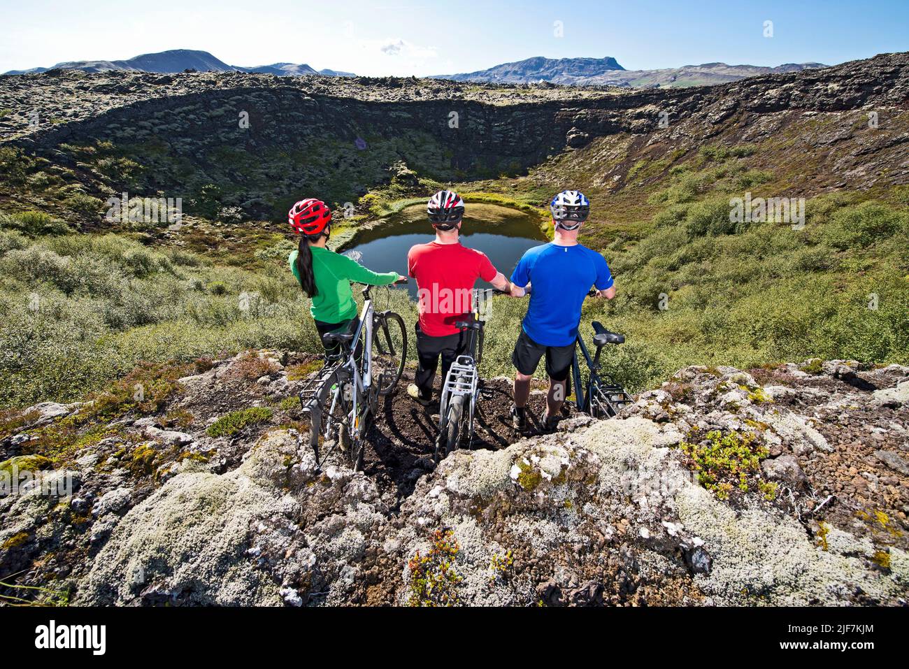 Drei Freunde erkunden auf ihren Mountainbikes einen Vulkankrater Stockfoto