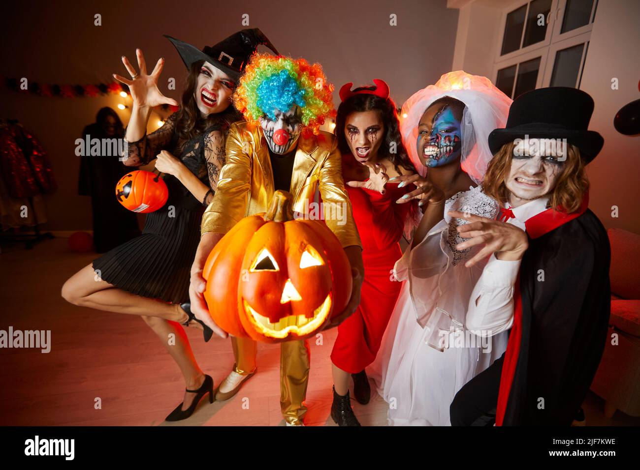 Eine Gruppe junger, glücklicher Freunde in Kostümen an Halloween, die sich auf der Party amüsieren und gruselige Gesichter machen. Stockfoto