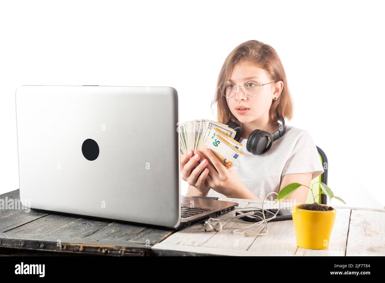 Kauf von Waren und Dienstleistungen über das Internet. Mädchen mit Geld in der Nähe des Laptops Buche. Geld online ausgeben. Stockfoto
