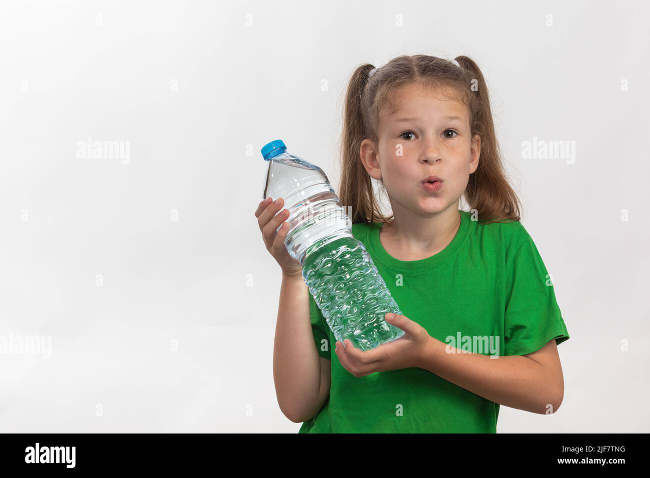 Kleines Mädchen mit einer Plastikwasserflasche. Hydrat und gesund bleiben. Blick in die Kamera. Stockfoto