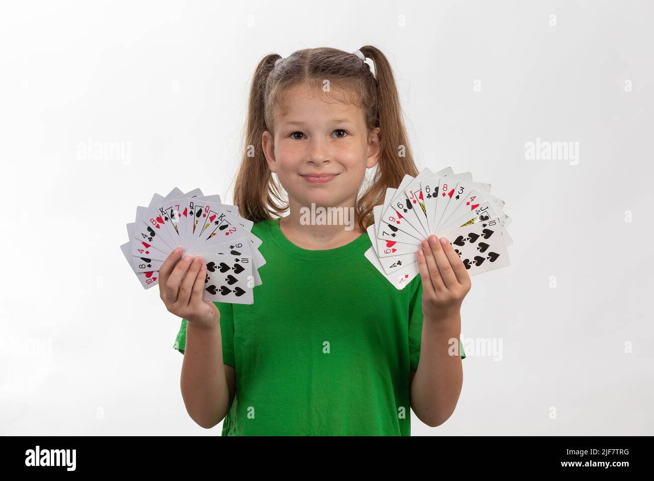Nahaufnahme Porträt von kaukasischen Mädchen mit Spielkarten. Isoliert auf weißem Hintergrund. Konzept für die Kindheit. Freizeit, Spaß, Hobby, Mädchen Zauberer. Stockfoto