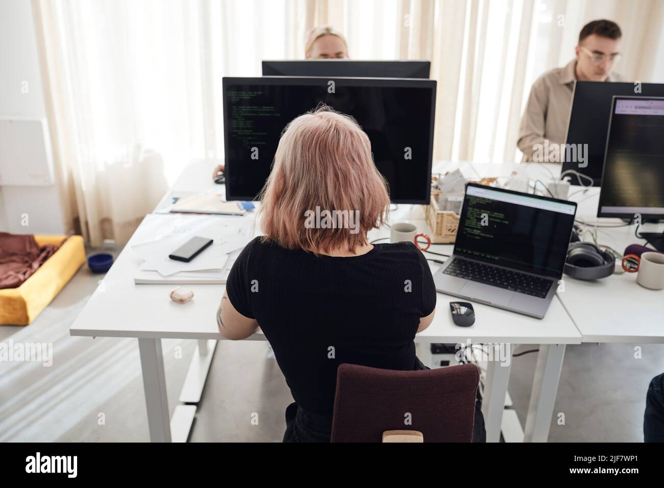 Rückansicht einer Geschäftsfrau, die am Computer arbeitet, während sie am Schreibtisch im Büro sitzt Stockfoto