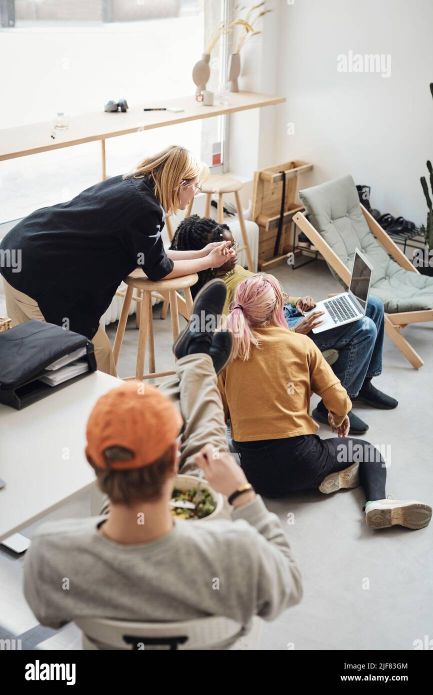 Junge Computerprogrammierer diskutieren über Laptop, während Geschäftsmann zu Mittag im Büro essen Stockfoto