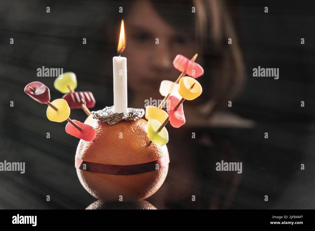 Ein kleines Mädchen schaut sich den Orange Christingle an, den sie gemacht hat. Selektiver Fokus. Stockfoto