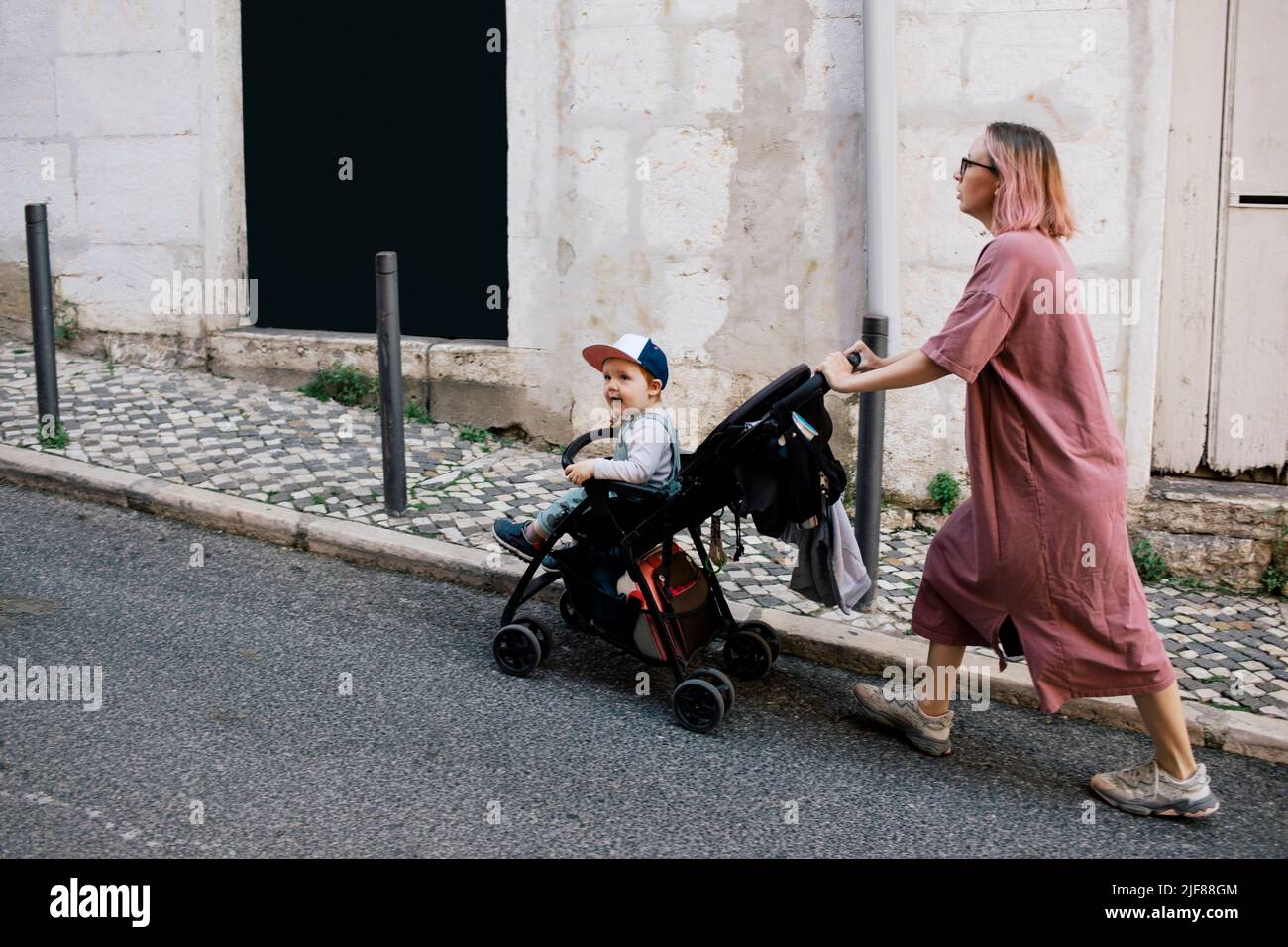 Mutter schiebt Sohn in Kinderwagen auf der Straße Stockfoto
