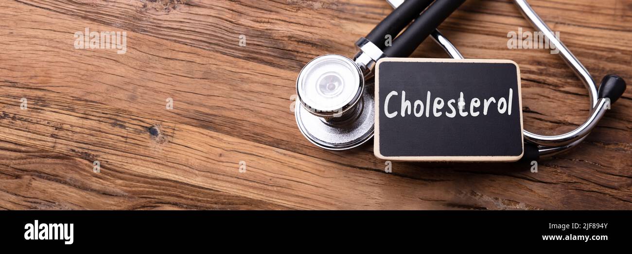 Cholesterin Wort auf Schiefer mit Stethoskop auf Holztisch geschrieben Stockfoto