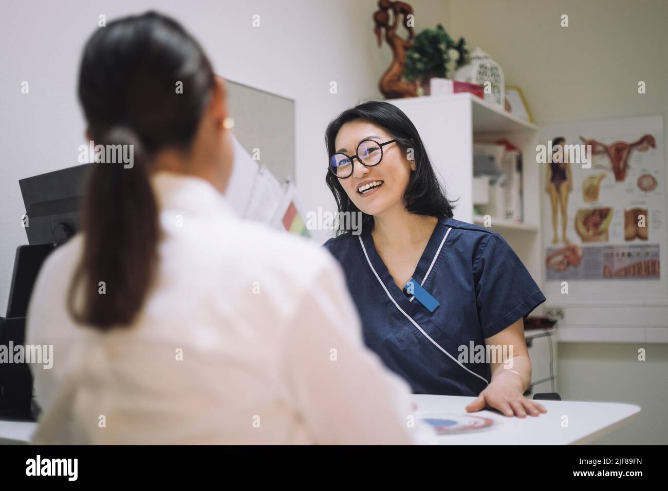 Glückliche Ärztin trägt Brillen Gespräch mit Patienten in der medizinischen Klinik Stockfoto