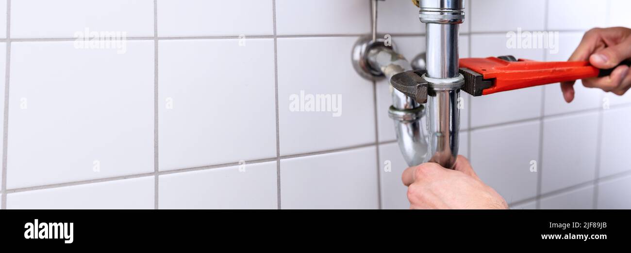 In der Nähe von einem Klempner Hand Instandsetzung Waschbecken mit verstellbarer Schraubenschlüssel Stockfoto