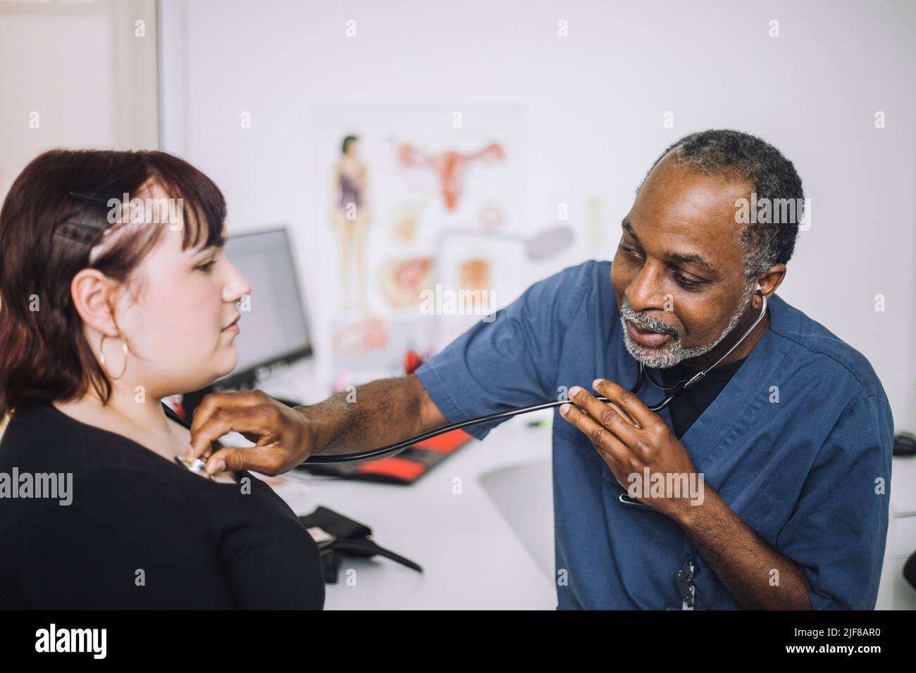 Männlicher Gesundheitsexperte mit Stethoskop, der weibliche Patienten in der Klinik untersucht Stockfoto