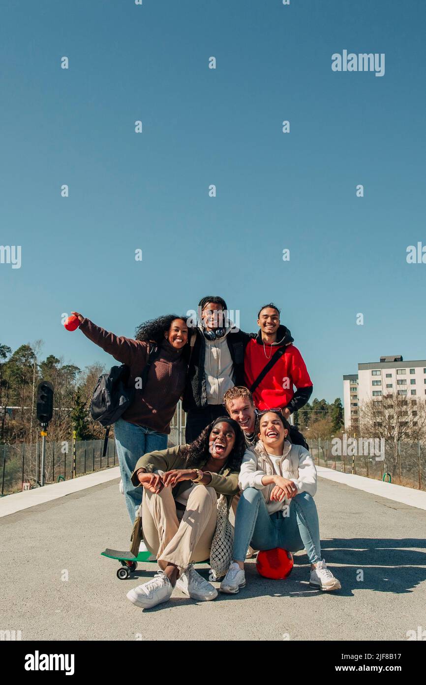 Glückliche multirassische Freunde, die am sonnigen Tag am Bahnhofssteig vor dem klaren blauen Himmel Spaß haben Stockfoto