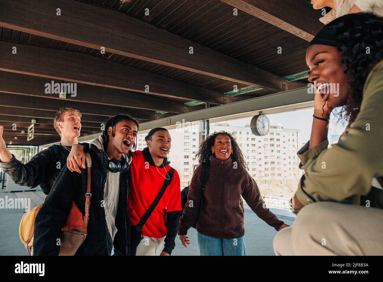 Spielerische, multirassische junge Freunde singen auf dem Bahnhofssteig Stockfoto