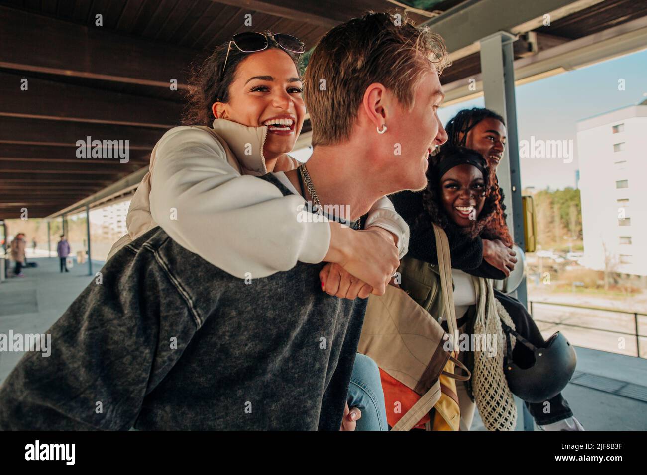 Glückliche spielerische multirassische Freunde Huckepack einander auf Bahnhofsplattform Stockfoto