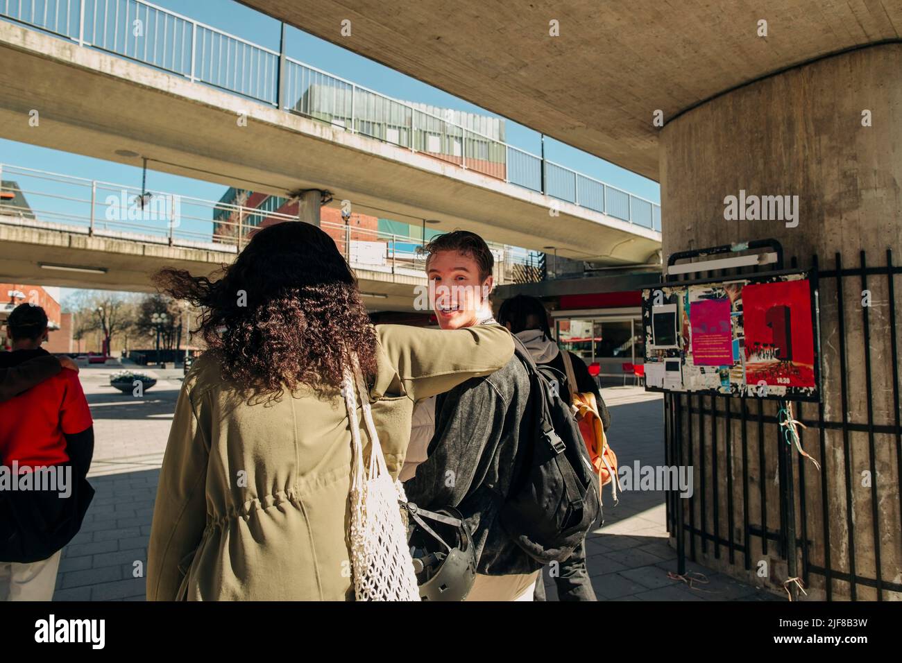 Mann schaut über die Schulter, während er mit einer Freundin auf der Straße läuft Stockfoto