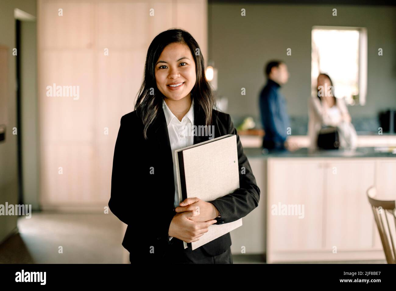 Porträt einer Verkäuferin mit einem Ordner, der in einem neuen Zuhause steht Stockfoto