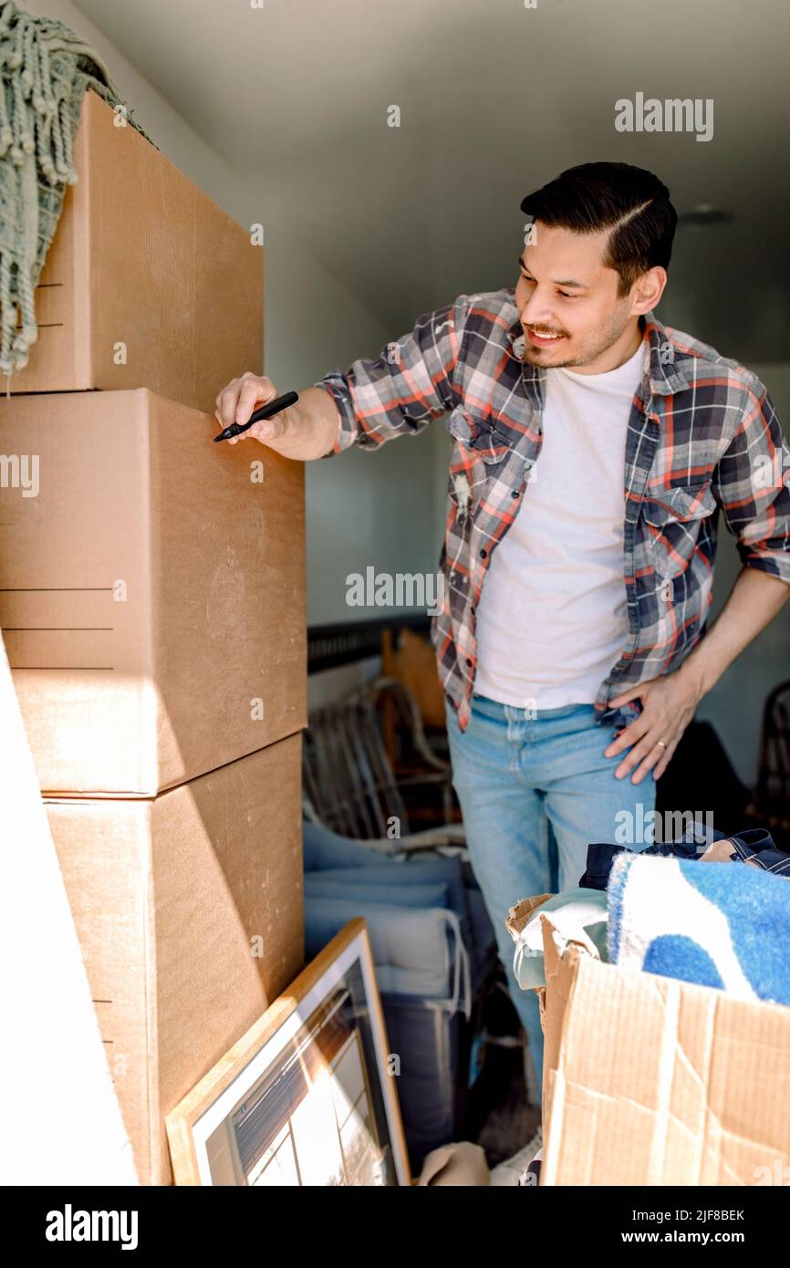 Mann, der auf Karton schreibt, während er im Lastwagen steht Stockfoto