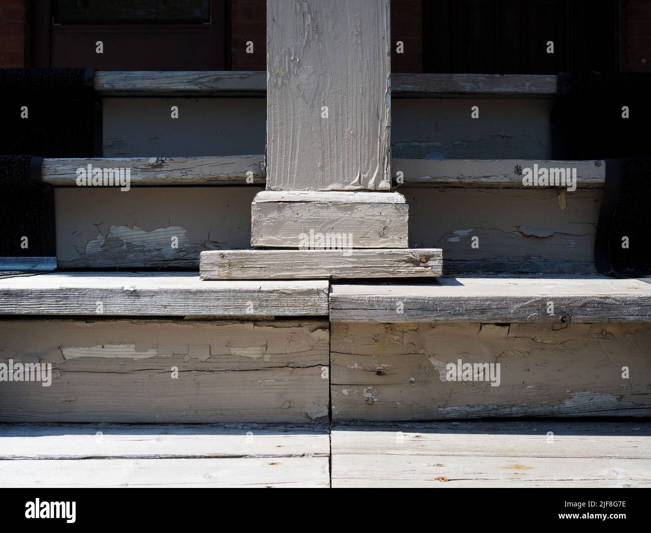 Abgenutzte und verwitterte graue Holztreppe und Säule, die zu einer Veranda und Haustür führt. Stockfoto