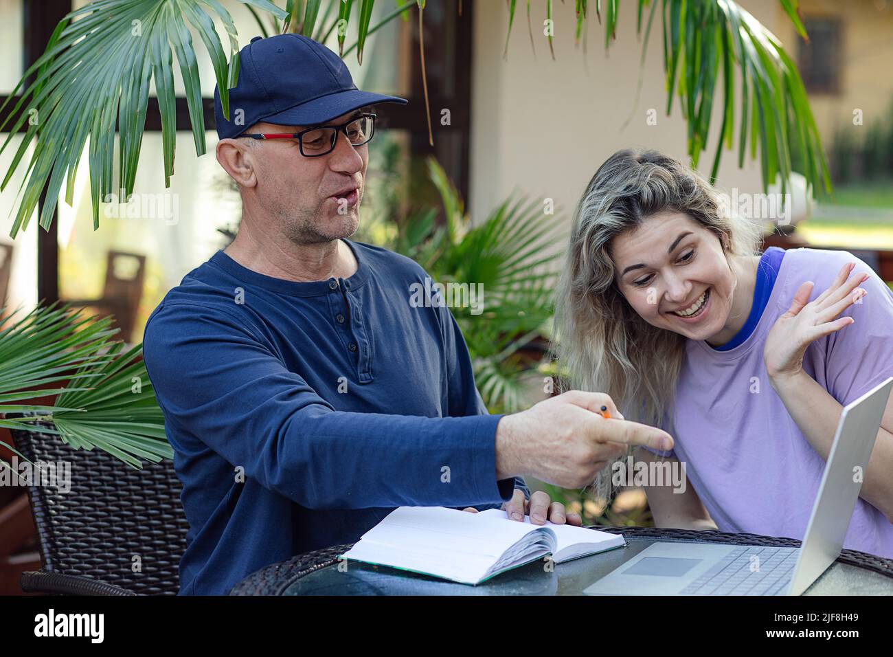 Porträt einer lächelnden Familie. Mann mittleren Alters Vater sitzt im Café, zeigt auf Laptop, diskutieren mit jungen Frau. Stockfoto
