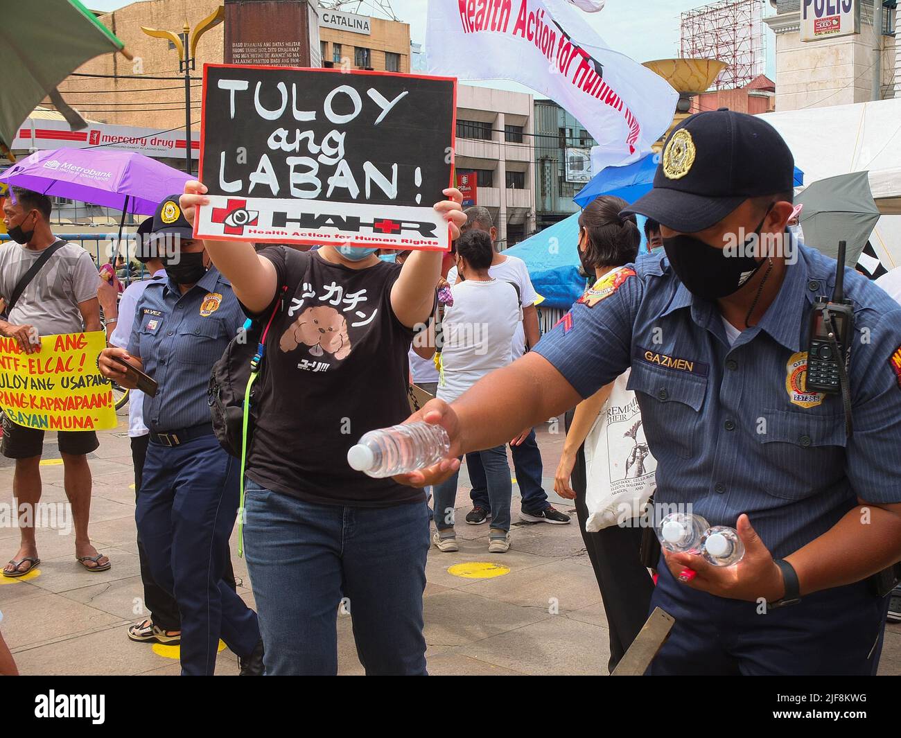 Manila, Philippinen. 30.. Juni 2022. Ein Polizist sah, wie er den Demonstranten kostenloses Mineralwasser gab. Militante Gruppen veranstalteten am Tag der Amtseinführung des gewählten Präsidenten Ferdinand 'Bongbong' Marcos Jr. einen Protest auf der Plaza Miranda in Quiapo. Die Hauptagenda des Protests war die Forderung nach Rechenschaftspflicht der kommenden Regierung gegenüber den Forderungen der Wirtschaft und den Verbrechen, die unter der Diktatur des begangen wurden Später Ferdinand Marcos Sr. (Foto: Josefiel Rivera/SOPA Images/Sipa USA) Quelle: SIPA USA/Alamy Live News Stockfoto