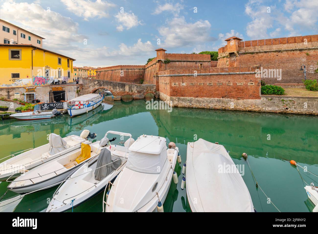 Boote säumen die überfüllten Kanäle neben der Neuen Festung und einem Café am Wasser an der Küste der toskanischen Stadt Livorno, Italien. Stockfoto