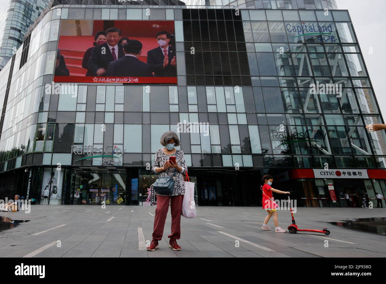 Ein Bildschirm zeigt Chinas Präsident Xi Jinping und Hongkongs neuen Chef John Lee während einer Zeremonie zur Einweihung der neuen Regierung Hongkongs in einem Einkaufszentrum in Peking, China, am 1. Juli 2022, am 25.. Jahrestag der Übergabe der Stadt von Großbritannien an China. REUTERS/Thomas Peter Stockfoto